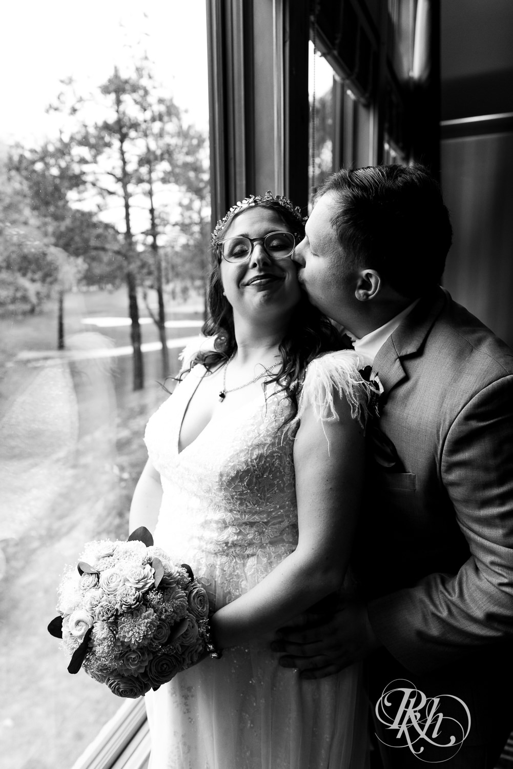 Bride and groom smile by the window on wedding day at Bunker Hills Event Center in Coon Rapids, Minnesota.