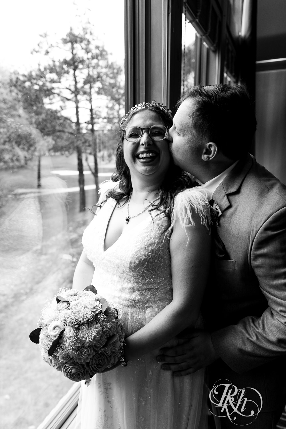 Bride and groom smile by the window on wedding day at Bunker Hills Event Center in Coon Rapids, Minnesota.