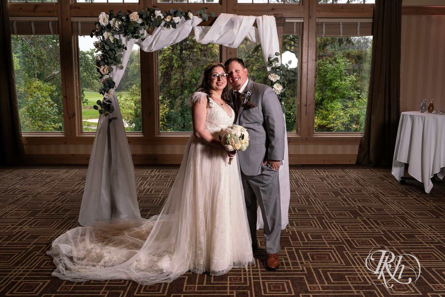 Bride and groom smile under arch on wedding day at Bunker Hills Event Center in Coon Rapids, Minnesota.