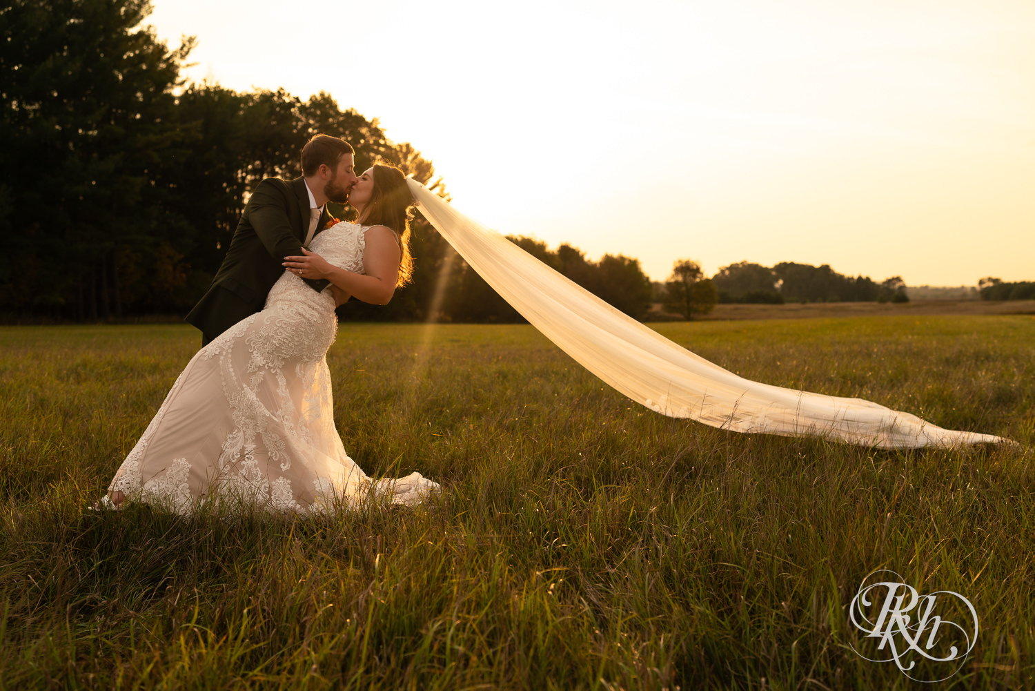 Bride and groom smile under veil in the sunset at Hayvn at Hay River in Boyceville, Wisconsin. 