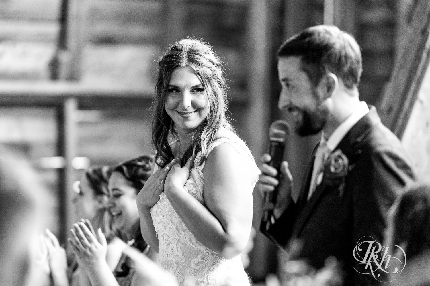 Bride, groom and wedding party smile during speeches at wedding reception at Hayvn at Hay River in Boyceville, Wisconsin. 