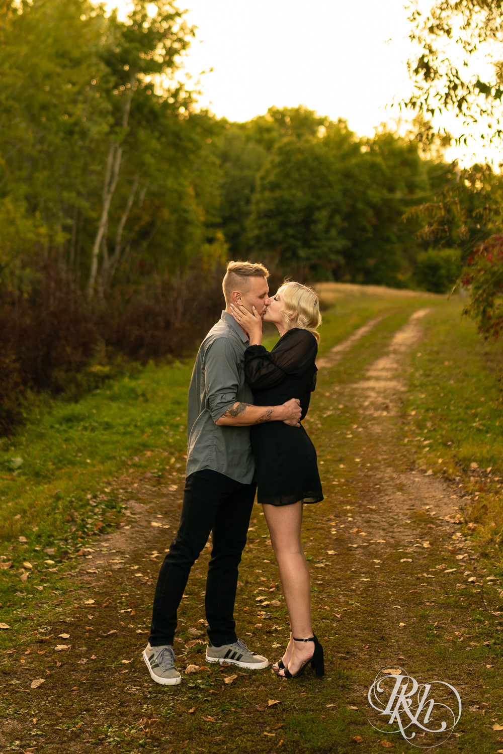 Blond woman in black dress and man in dress shirt damce during sunset engagement photos at Lebanon Hills Regional Park in Eagan, Minnesota.