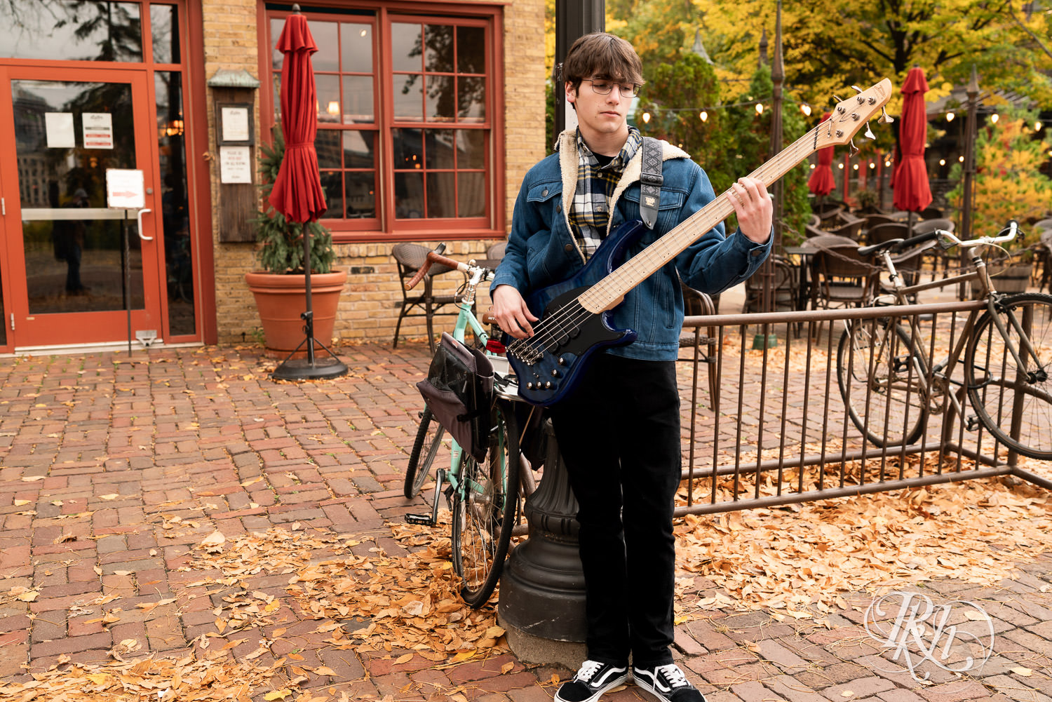 Senior boy smiles during downtown Minneapolis senior photography with cat and bass guitar.
