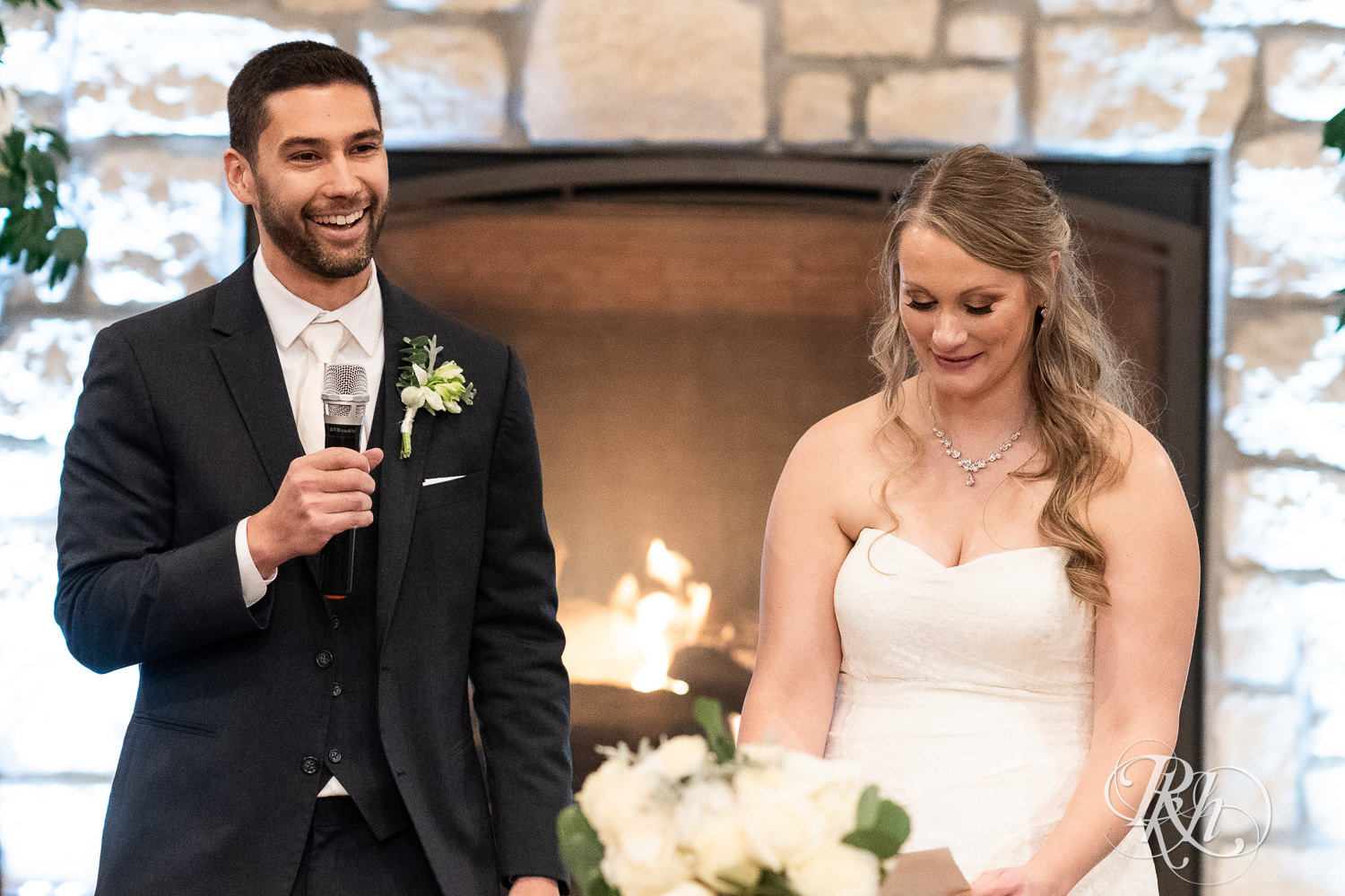 Bride and groom smile during speeches at wedding reception at Almquist Farm in Hastings, Minnesota.