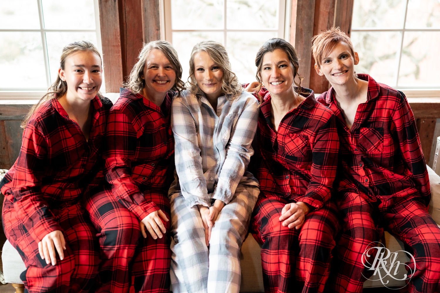 Bride snuggles with bridesmaids in flannel pajamas on wedding day at Almquist Farm in Hastings, Minnesota.