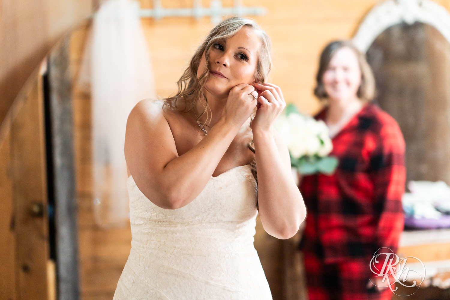 Bride puts in earrings on wedding day at Almquist Farm in Hastings, Minnesota.