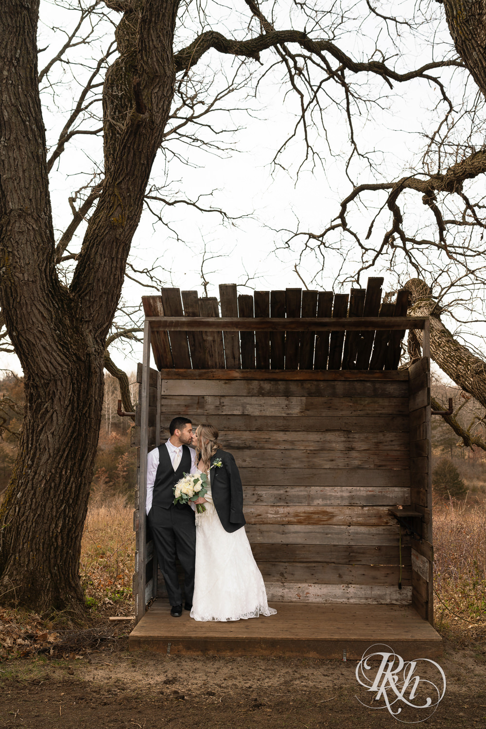 Bride and groom kiss in the woods on wedding day at Almquist Farm in Hastings, Minnesota.