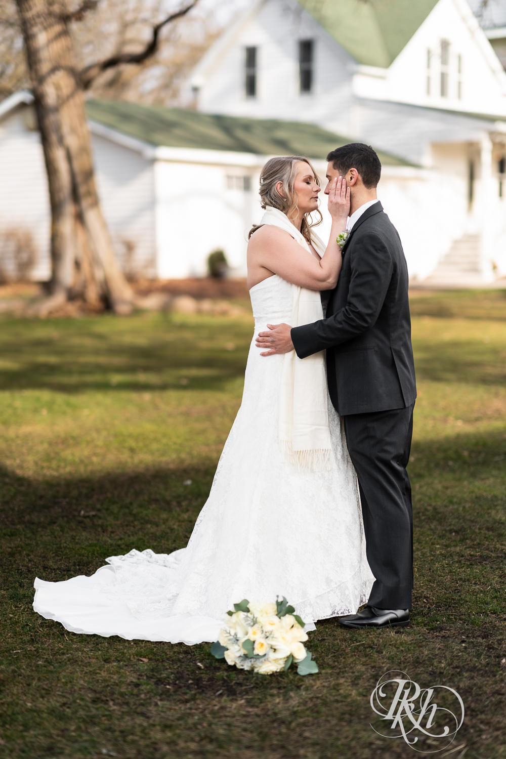 Bride and groom dance and kiss in front of a white farmhouse at Almquist Farm in Hastings, Minnesota.
