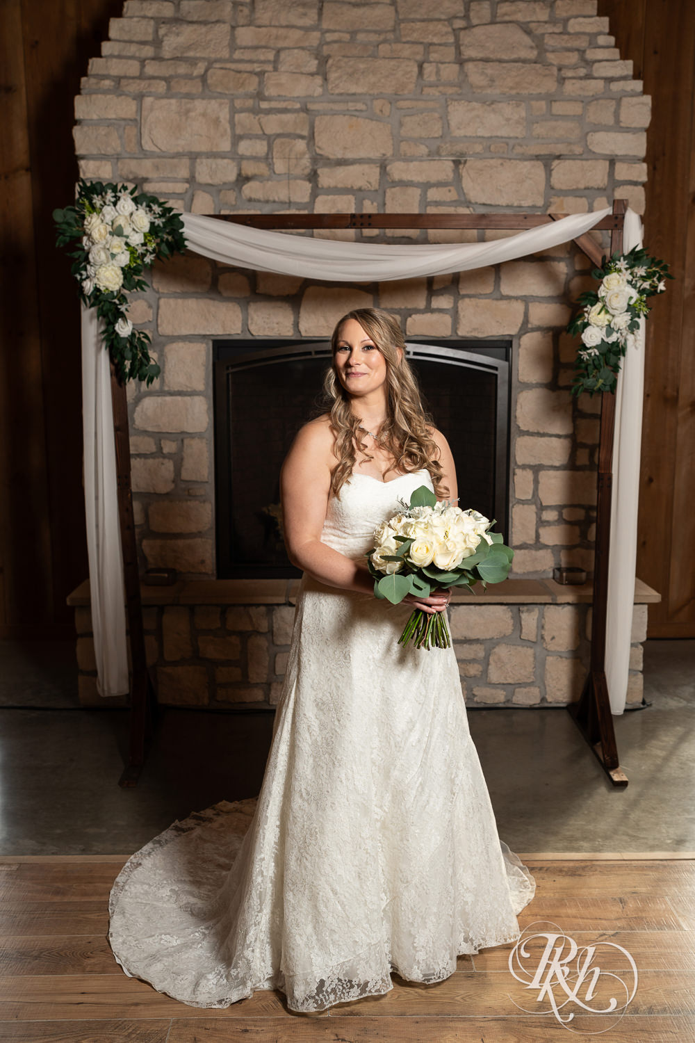 Bride smiles in front of a fireplace at Almquist Farm in Hastings, Minnesota.