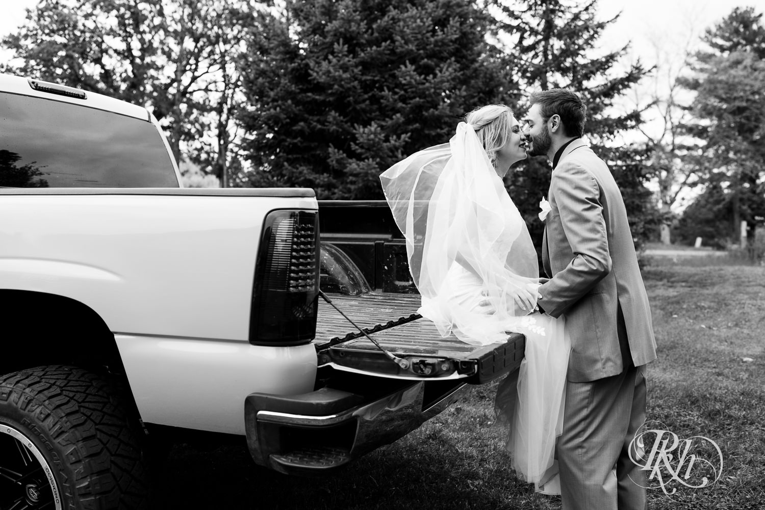 Bride and groom kiss in the back of a pickup truck on wedding day at Bunker Hills Event Center in Coon Rapids, Minnesota.