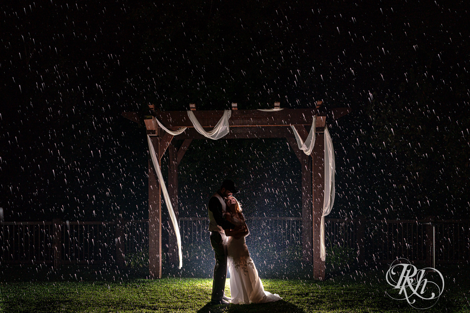 Bride and groom snuggle in the rain on wedding day at Bunker Hills Event Center in Coon Rapids, Minnesota.