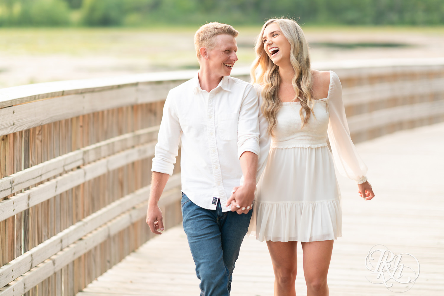 Man and woman in white and cowboy boots laugh walking on a bridge at Lebanon Hills Regional Park in Eagan, Minnesota.