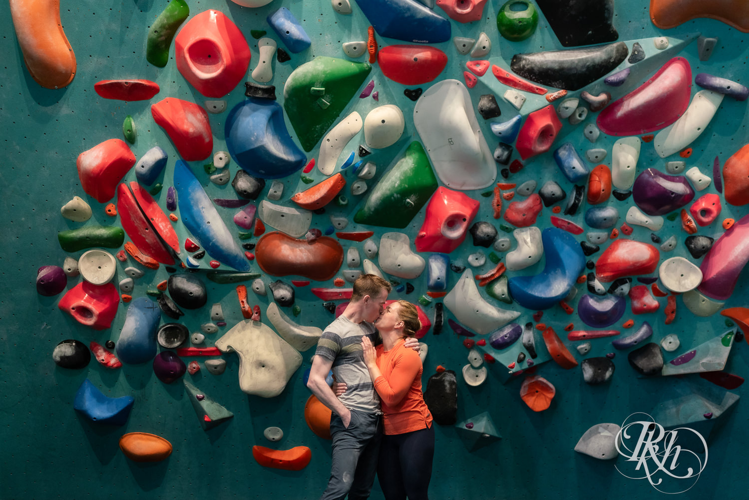 Man and woman kiss during engagement photography session at the Bouldering Project in Minneapolis, Minnesota.