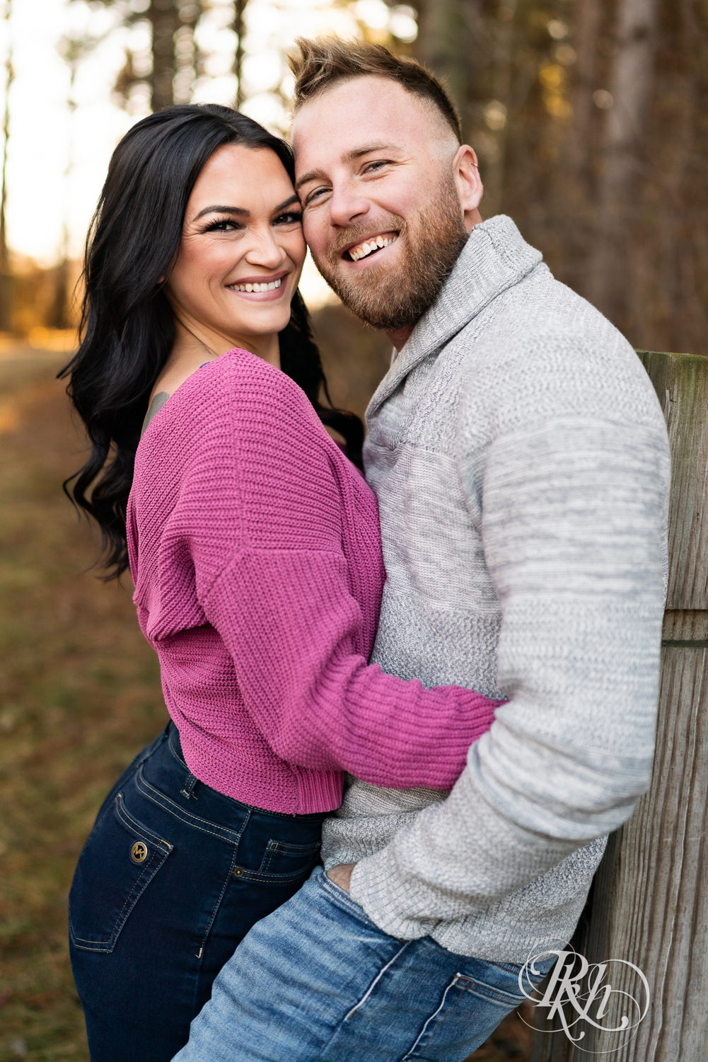 Man in sweater and jeans and woman in pink sweater and jeans smile at Lebanon Hills Regional Park in Eagan, Minnesota.