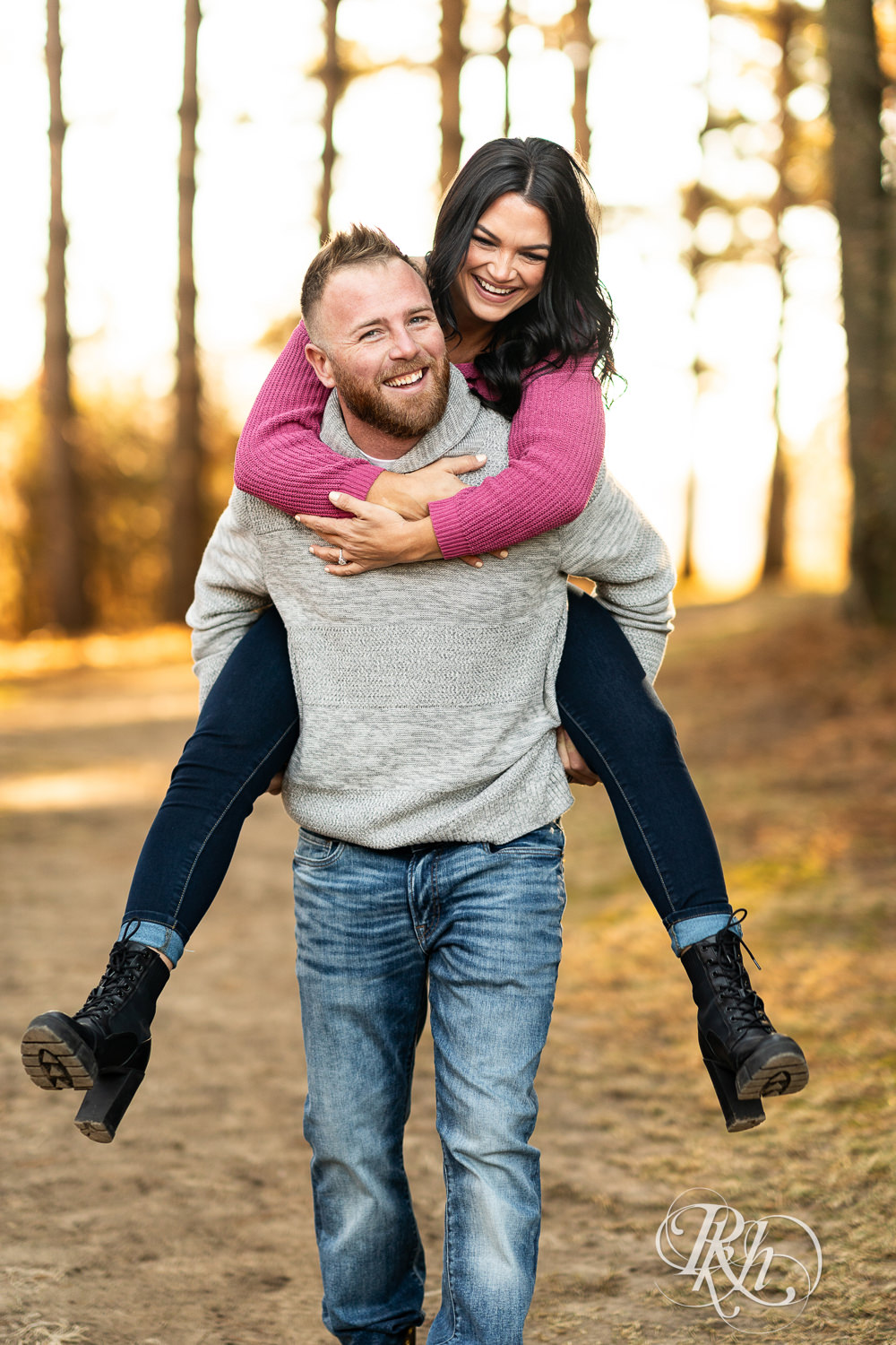 Man in sweater and jeans carries woman in pink sweater and jeans on his back at Lebanon Hills Regional Park in Eagan, Minnesota.