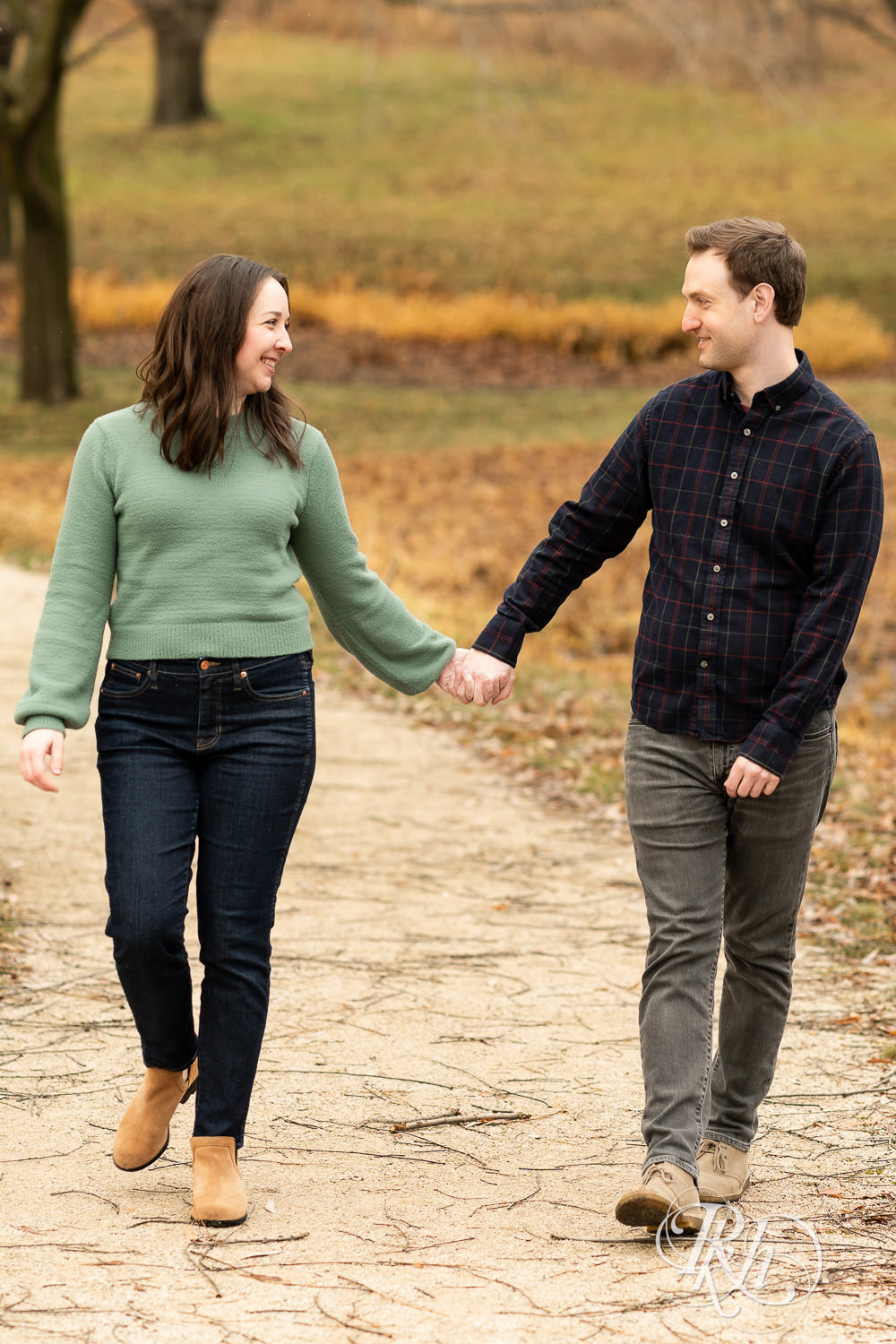 Man and woman walk holding hands during winter engagement photography at Minnesota Landscape Arboretum in Chaska, Minnesota.
