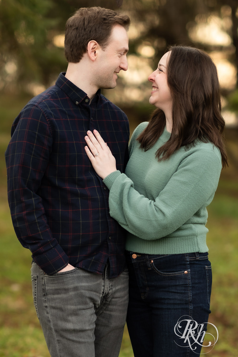 Man and woman smile during winter engagement photography at Minnesota Landscape Arboretum in Chaska, Minnesota.