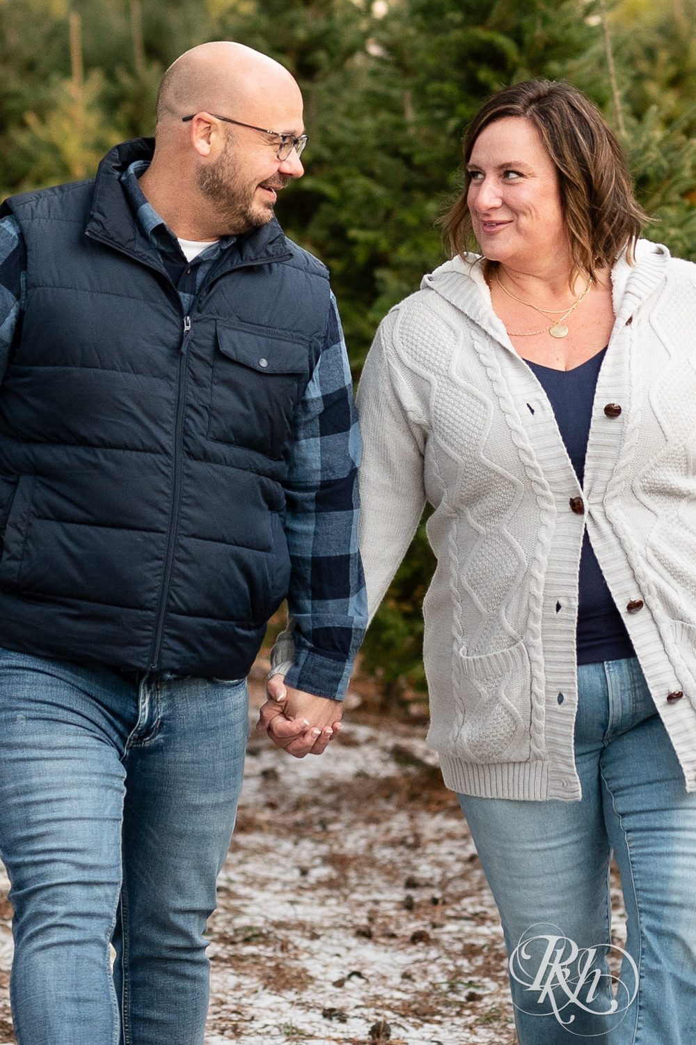 Black man and white woman walk holding hands and laughing at Hansen Tree Farm in Anoka, Minnesota.