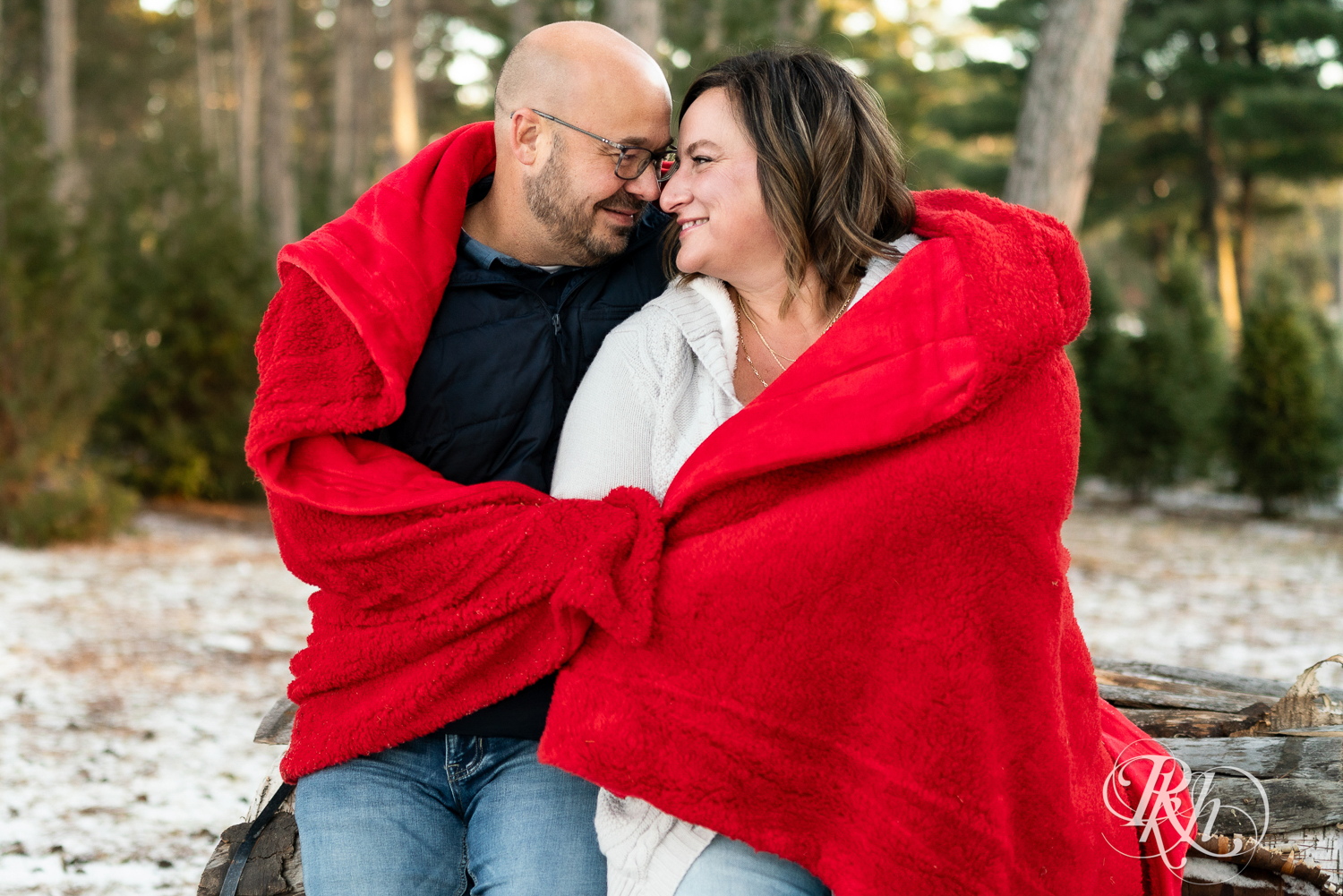 Black man and white woman snuggle in red blanket at Hansen Tree Farm in Anoka, Minnesota.