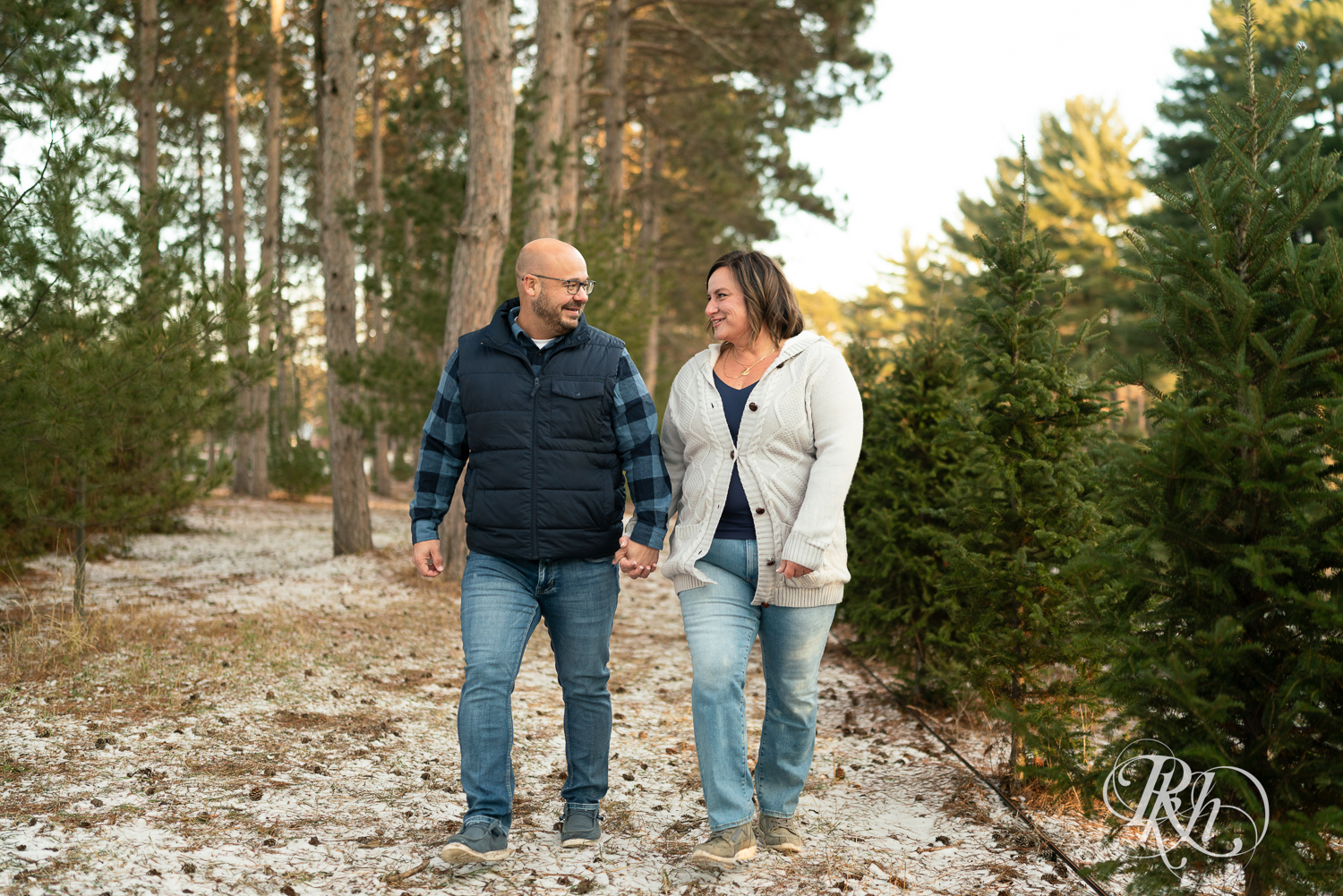 Black man and white woman walk holding hands and laughing at Hansen Tree Farm in Anoka, Minnesota.