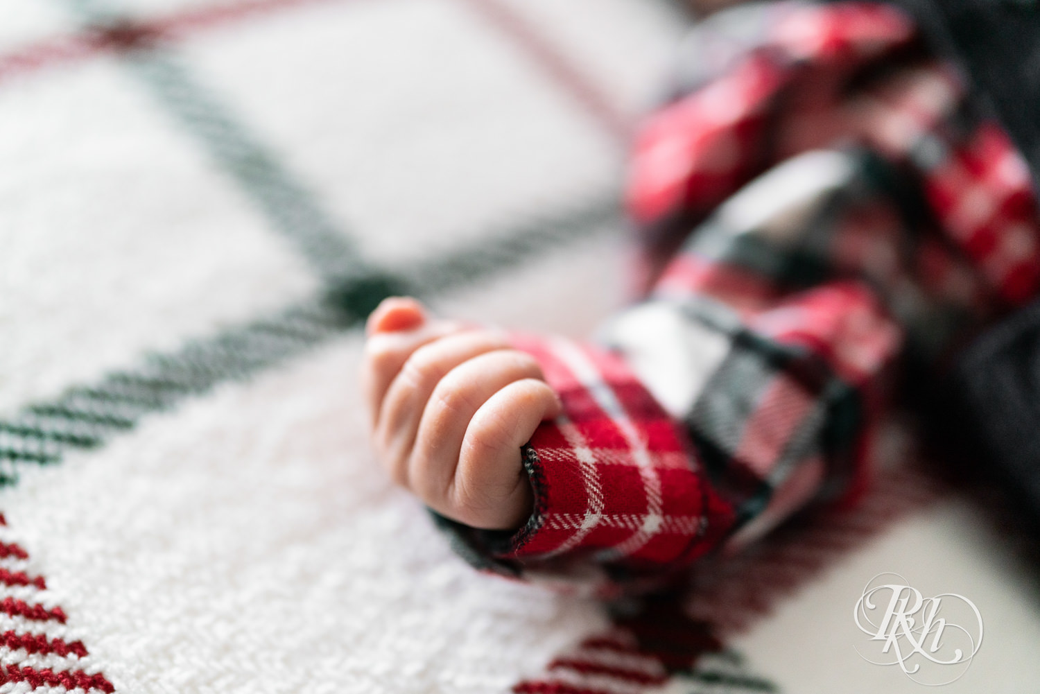 Newborn biracial baby dressed in flannel and overalls sleeps during newborn photography in Burnsville, Minnesota.