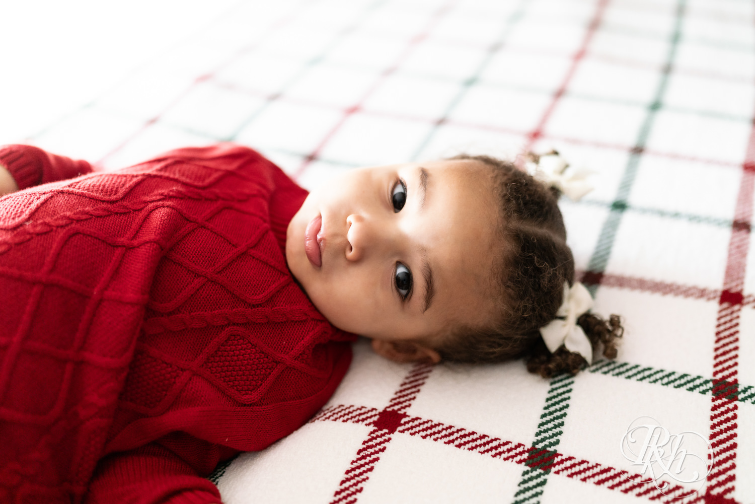 Little girl in red sweater looks at camera during photography in Burnsville, Minnesota.