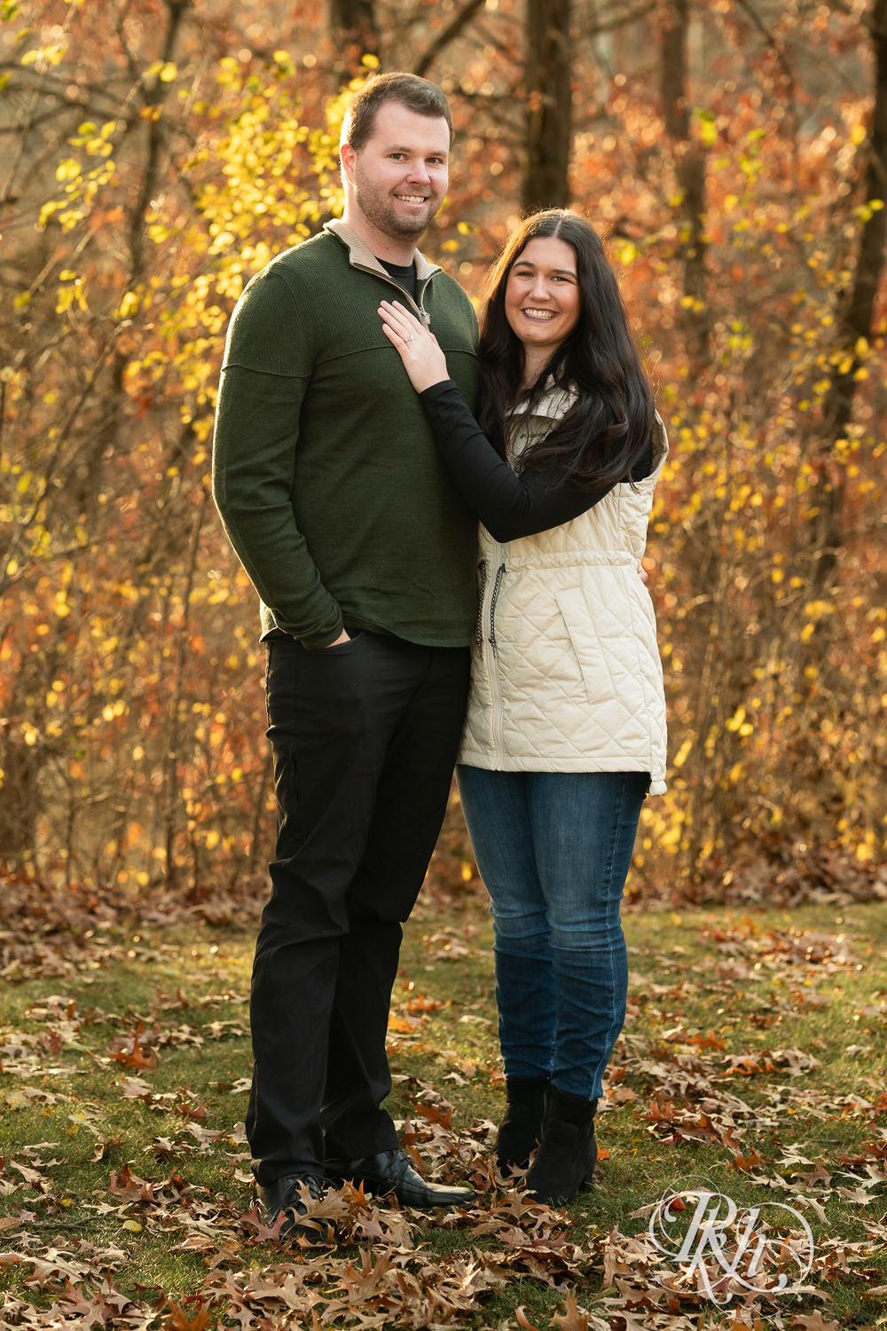 Man and woman smile at each other during chilly November engagement photography at Lebanon Hills in Eagan, Minnesota.