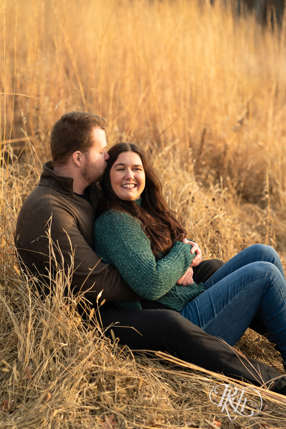 Man and woman smile and snuggle during winter engagement photography at Lebanon Hills in Eagan, Minnesota.