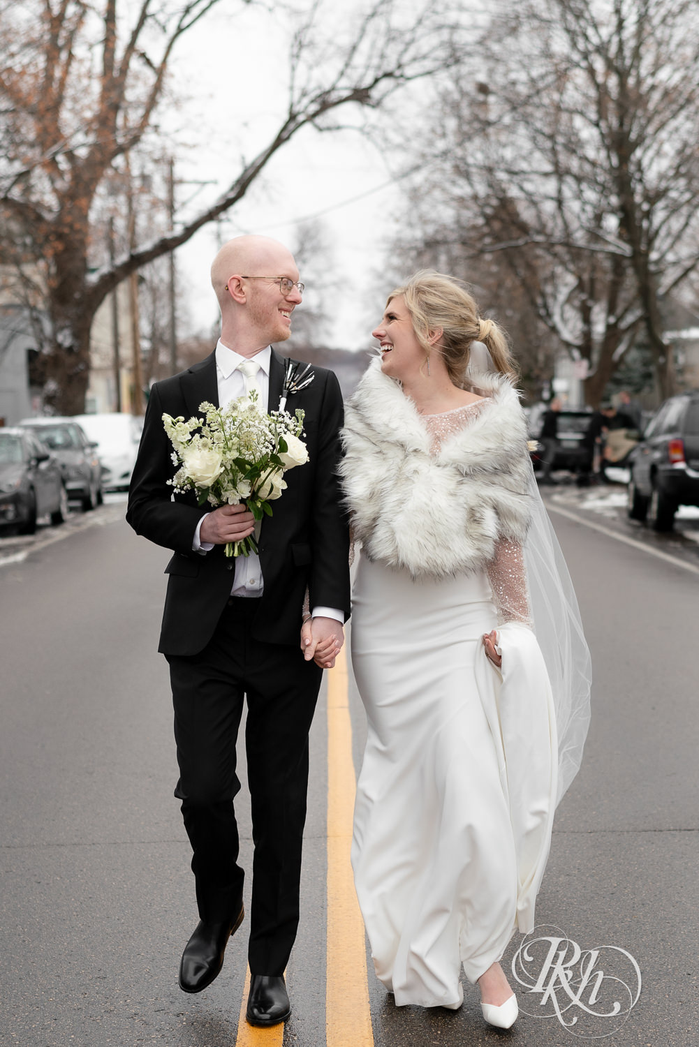 Bride and groom smile walking down the street in Saint Paul, Minnesota on winter wedding day.