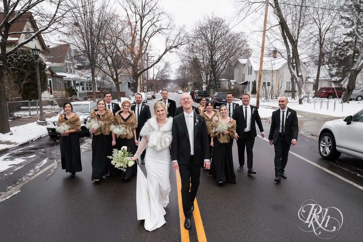 Wedding party smiles with bride and groom in the street in Saint Paul, Minnesota on winter wedding day.