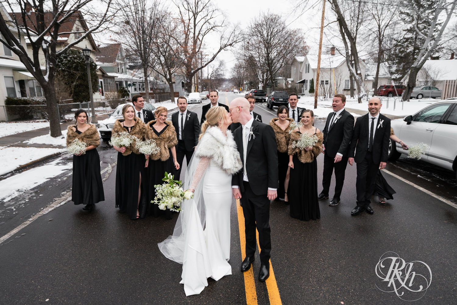 Wedding party smiles with bride and groom in the street in Saint Paul, Minnesota on winter wedding day.