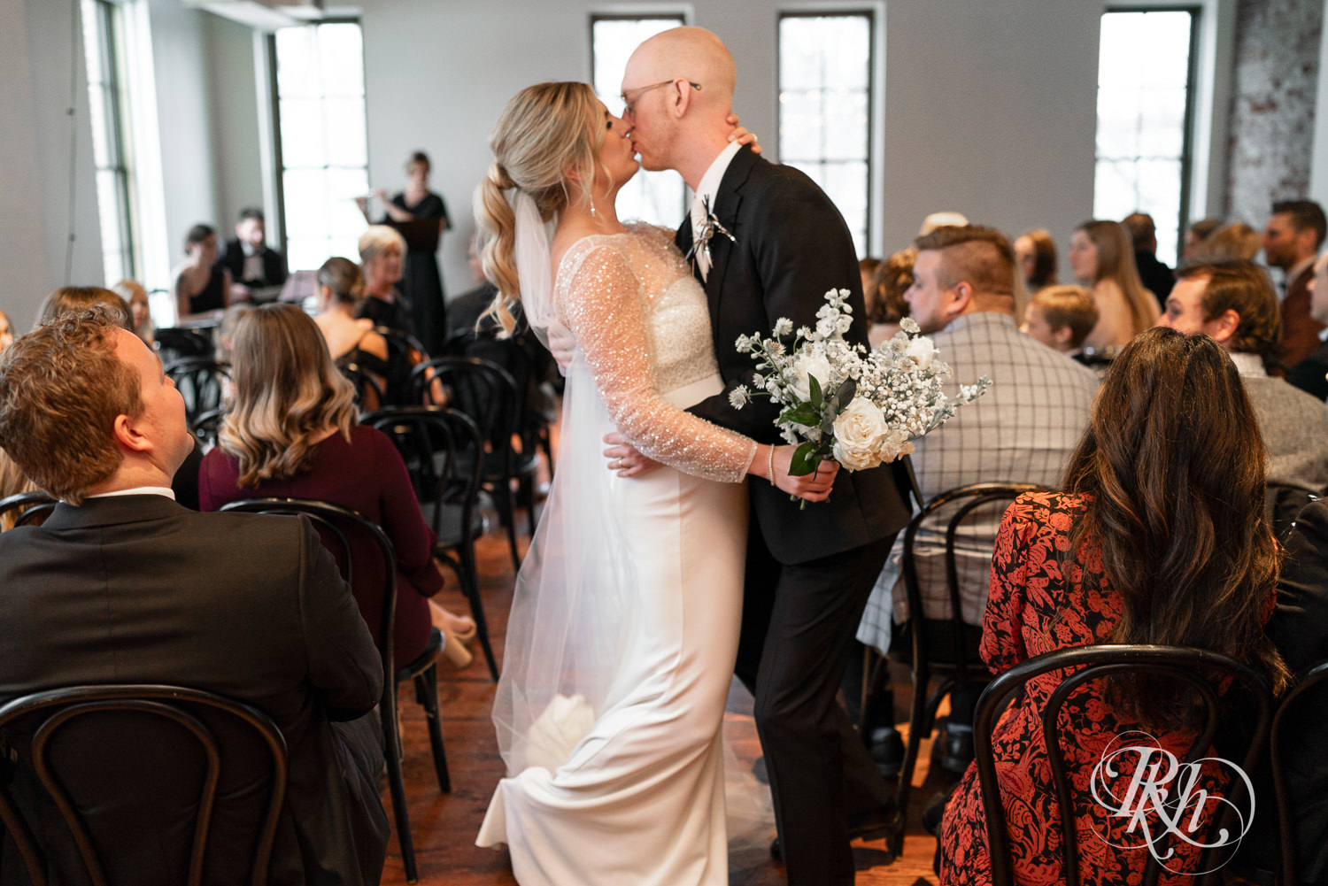 Bride and groom kiss during indoor wedding ceremony at Gatherings at Station 10 in Saint Paul, Minnesota.