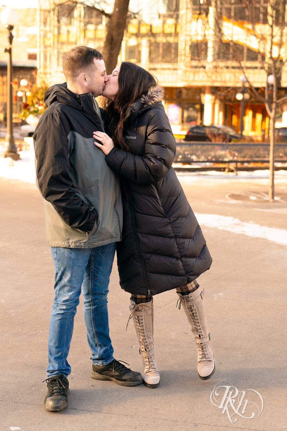 Man and woman in jackets kiss in Saint Paul, Minnesota during winter engagement session.