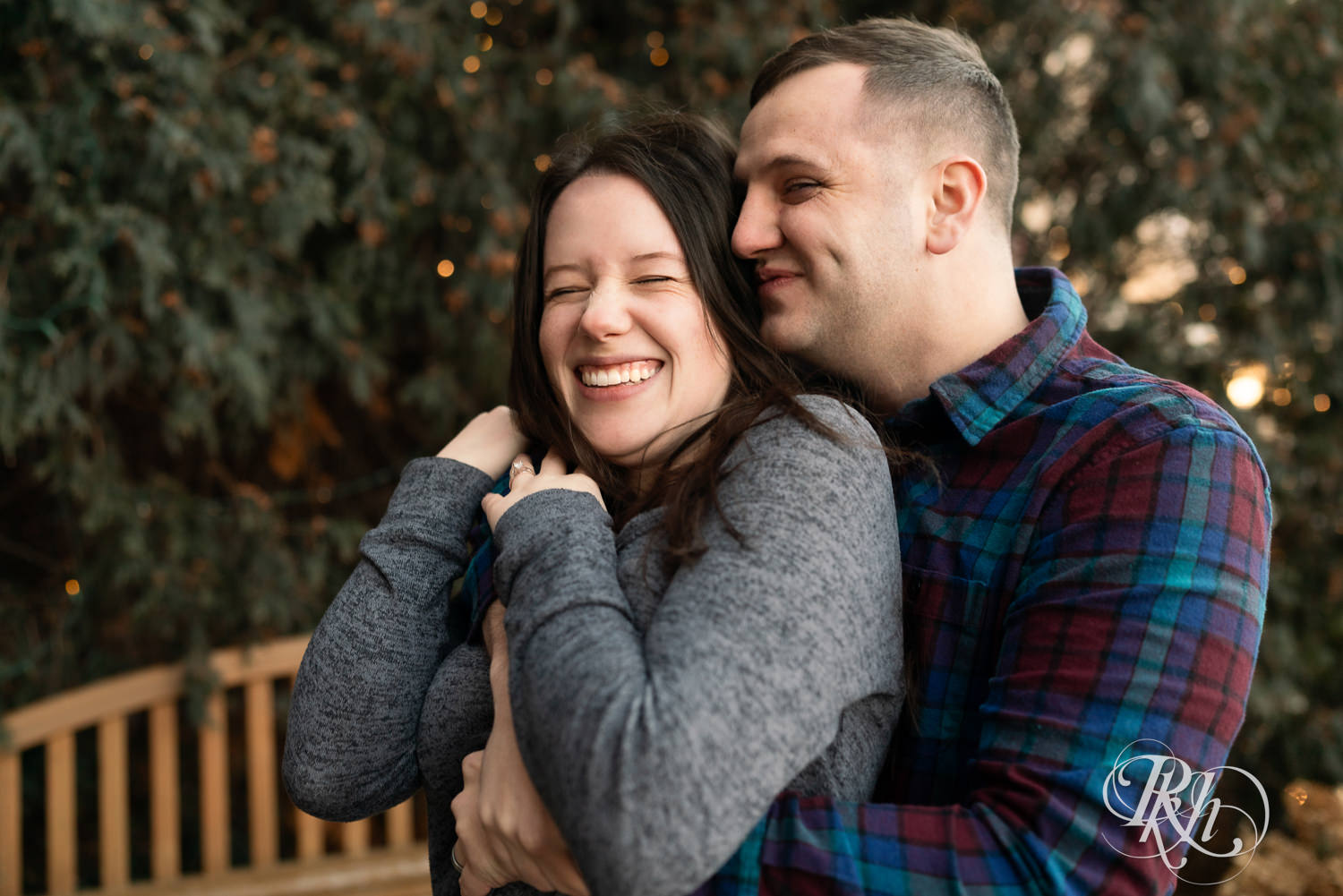 Man and woman in jackets snuggle and laugh during winter engagement photos at the Saint Paul Hotel in Saint Paul, Minnesota.