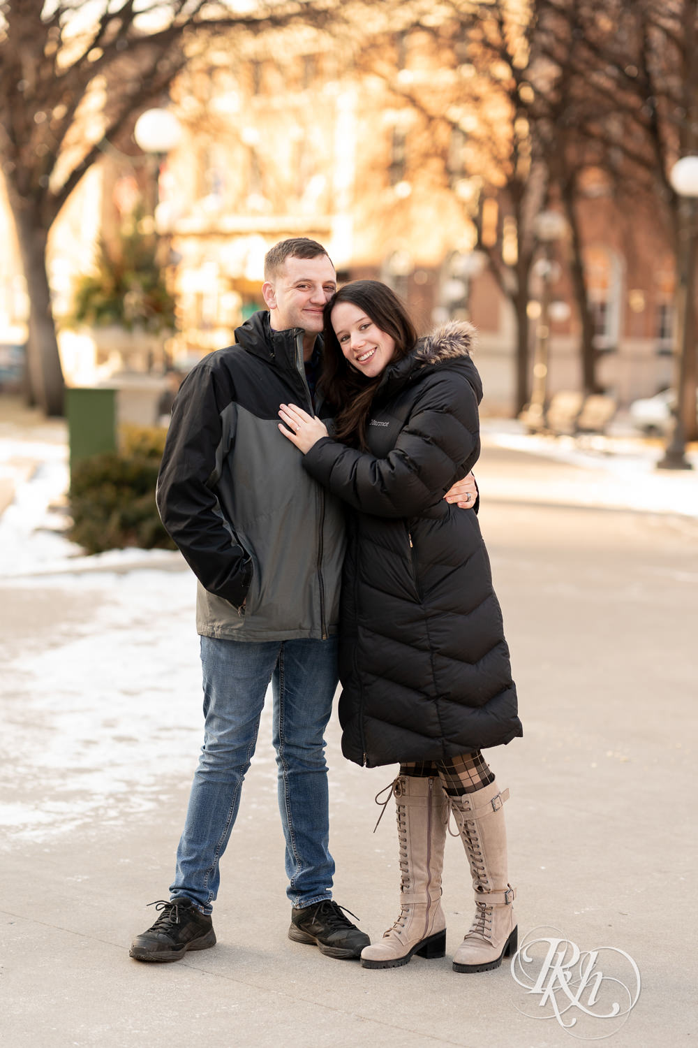 Man and woman in jackets smile in Saint Paul, Minnesota during winter engagement session.