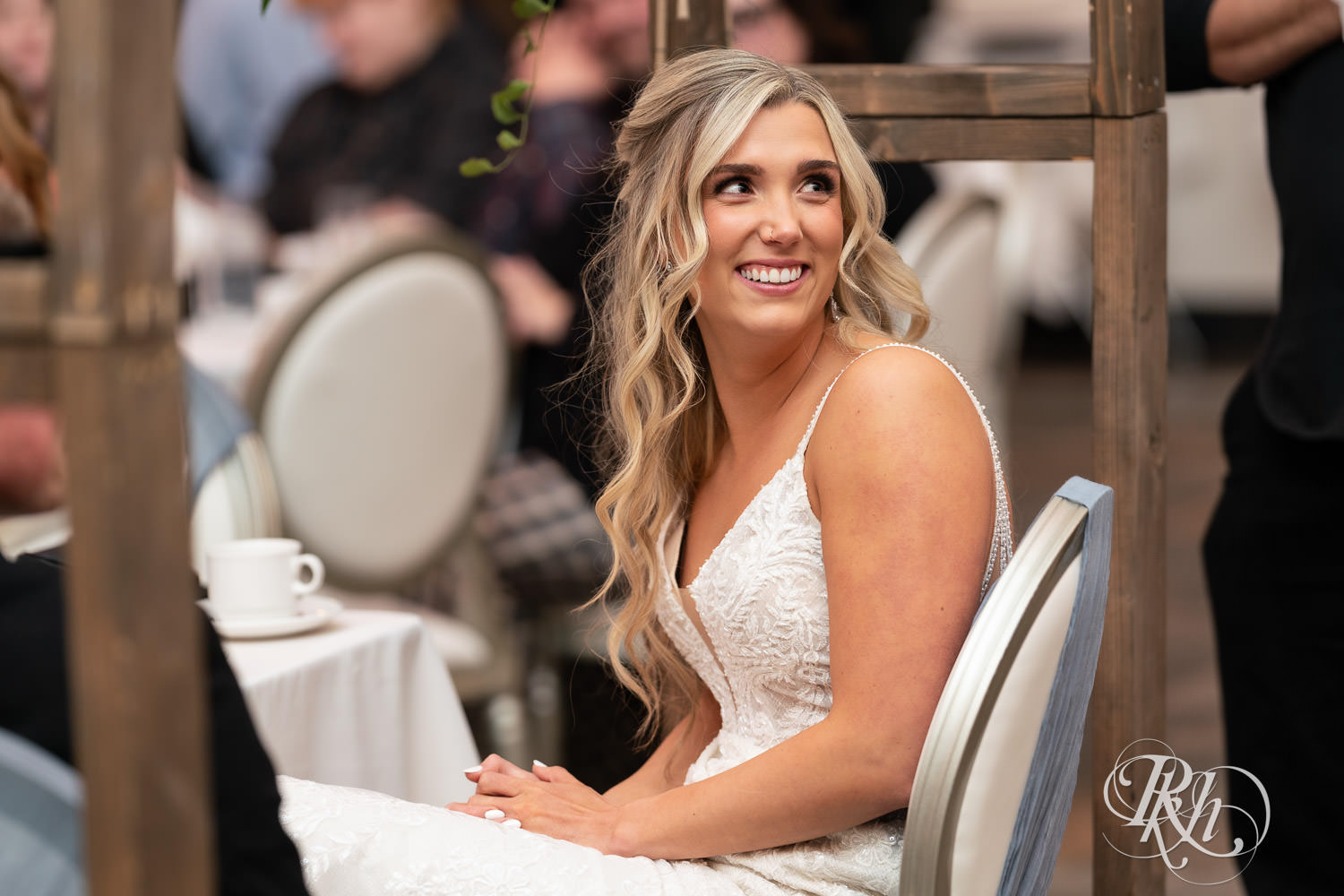 Bride smiles during speeches at wedding reception at Bavaria Downs in Chaska, Minnesota.