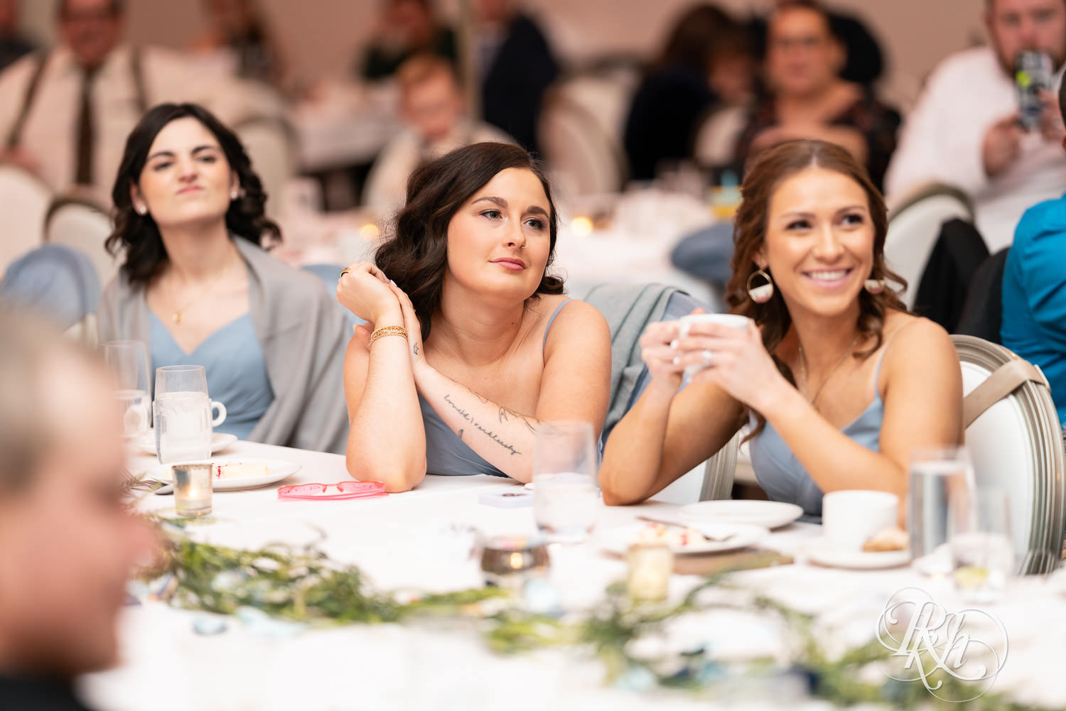 Bridesmaids smile during speeches at wedding reception at Bavaria Downs in Chaska, Minnesota.