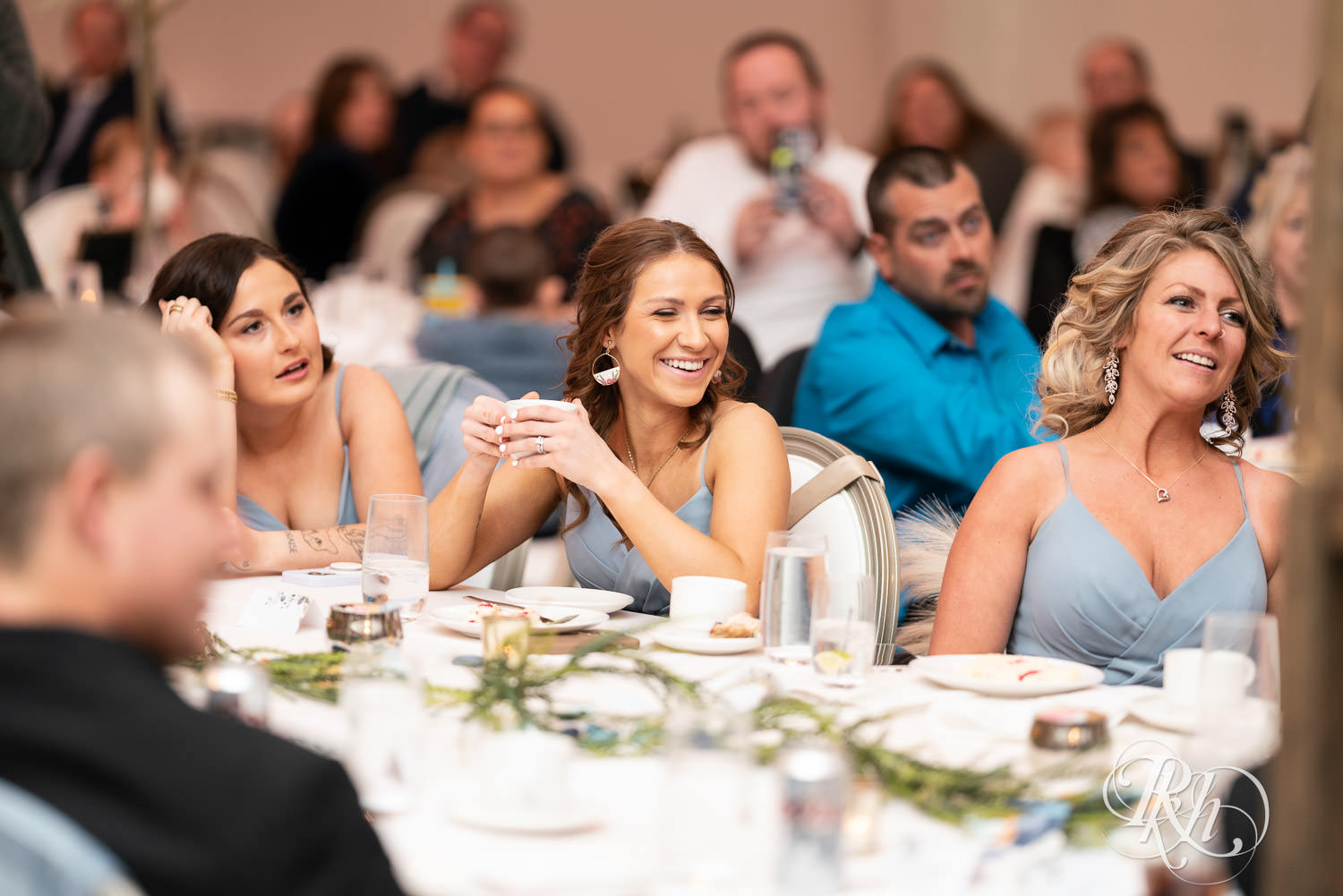 Bridesmaids smile during speeches at wedding reception at Bavaria Downs in Chaska, Minnesota.