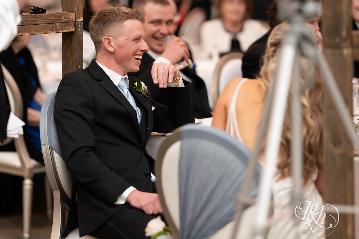 Groom smiles during speeches at wedding reception at Bavaria Downs in Chaska, Minnesota.