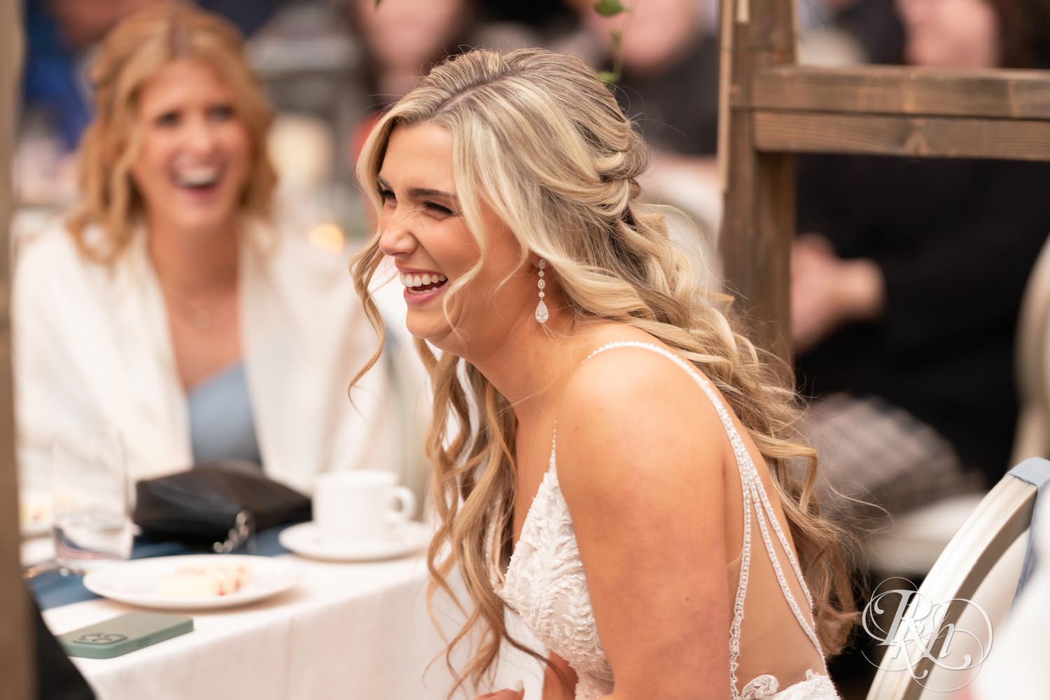 Bride smiles during speeches at wedding reception at Bavaria Downs in Chaska, Minnesota.
