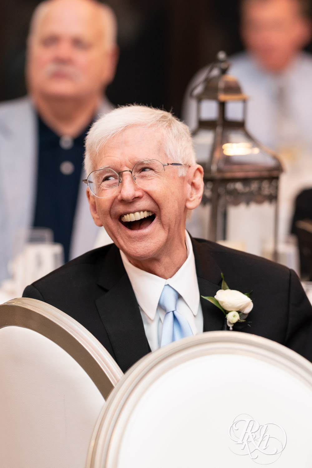 Guests smile during speeches at wedding reception at Bavaria Downs in Chaska, Minnesota.