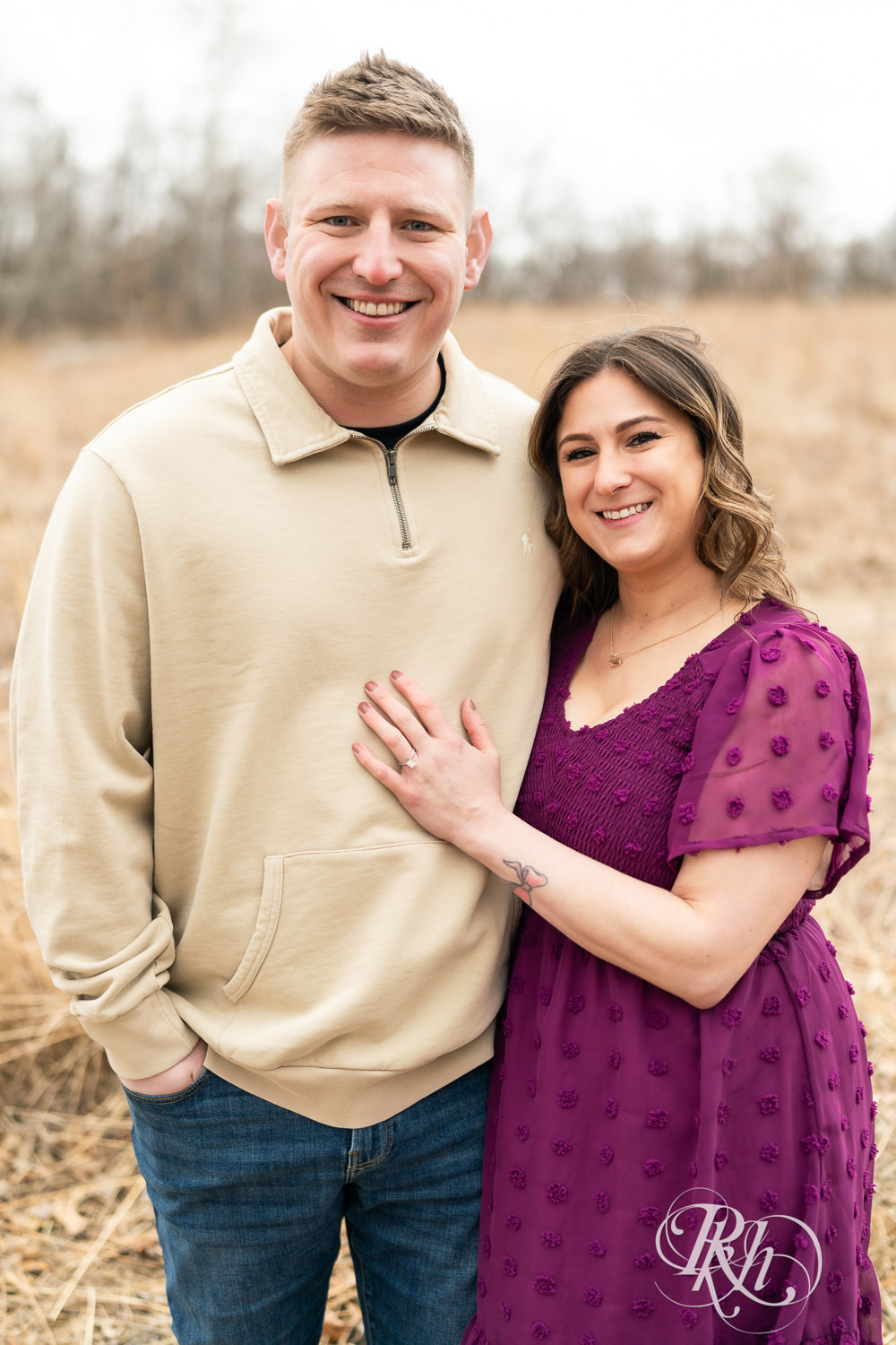Man in jeans and woman in magenta dress smile during March engagement photography in Eagan, Minnesota.