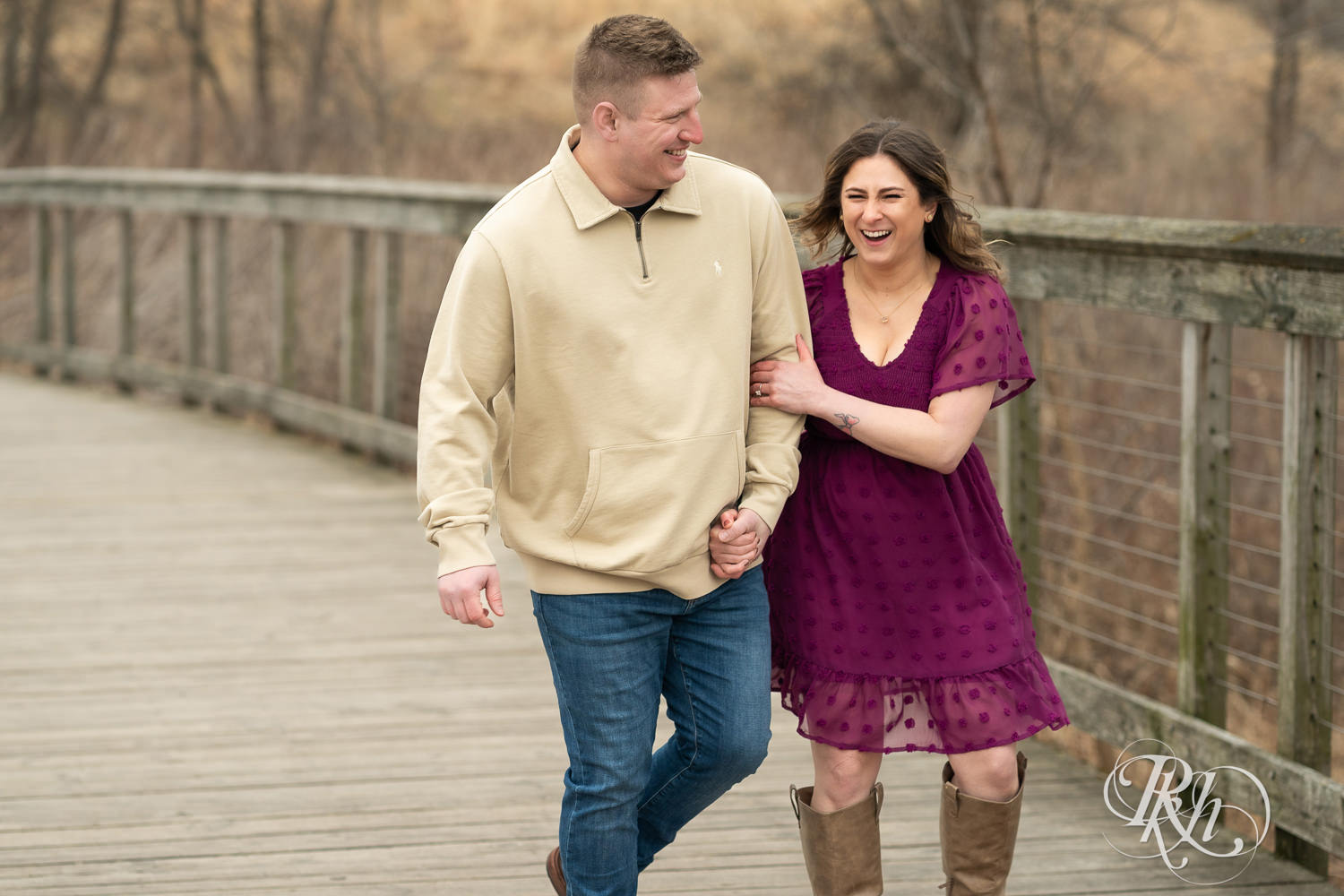 Man in jeans and woman in magenta dress laugh while walking on a bridge in Lebanon Hills in Eagan, Minnesota.