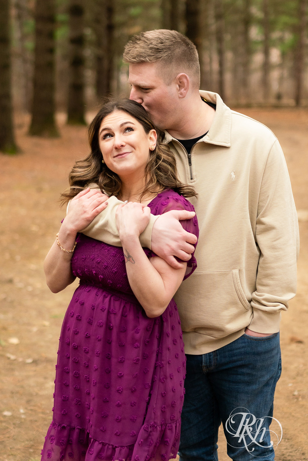 Man in jeans and woman in magenta dress smile during engagement photos in Lebanon Hills in Eagan, Minnesota.