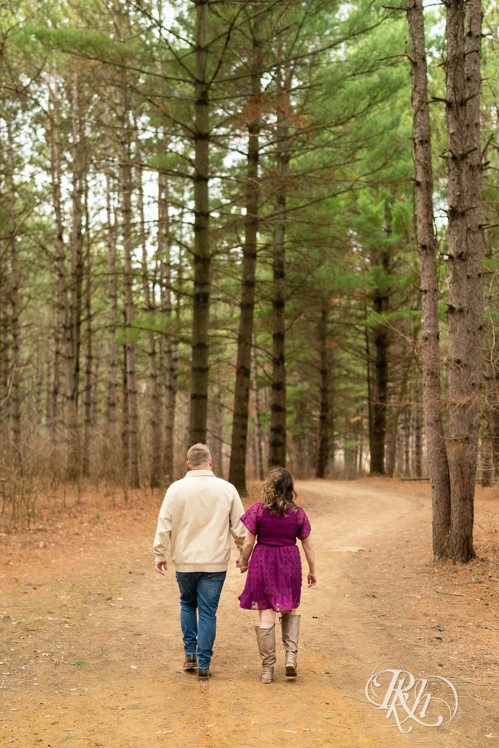 Man in jeans and woman in magenta dress walk through the woods in Lebanon Hills in Eagan, Minnesota.