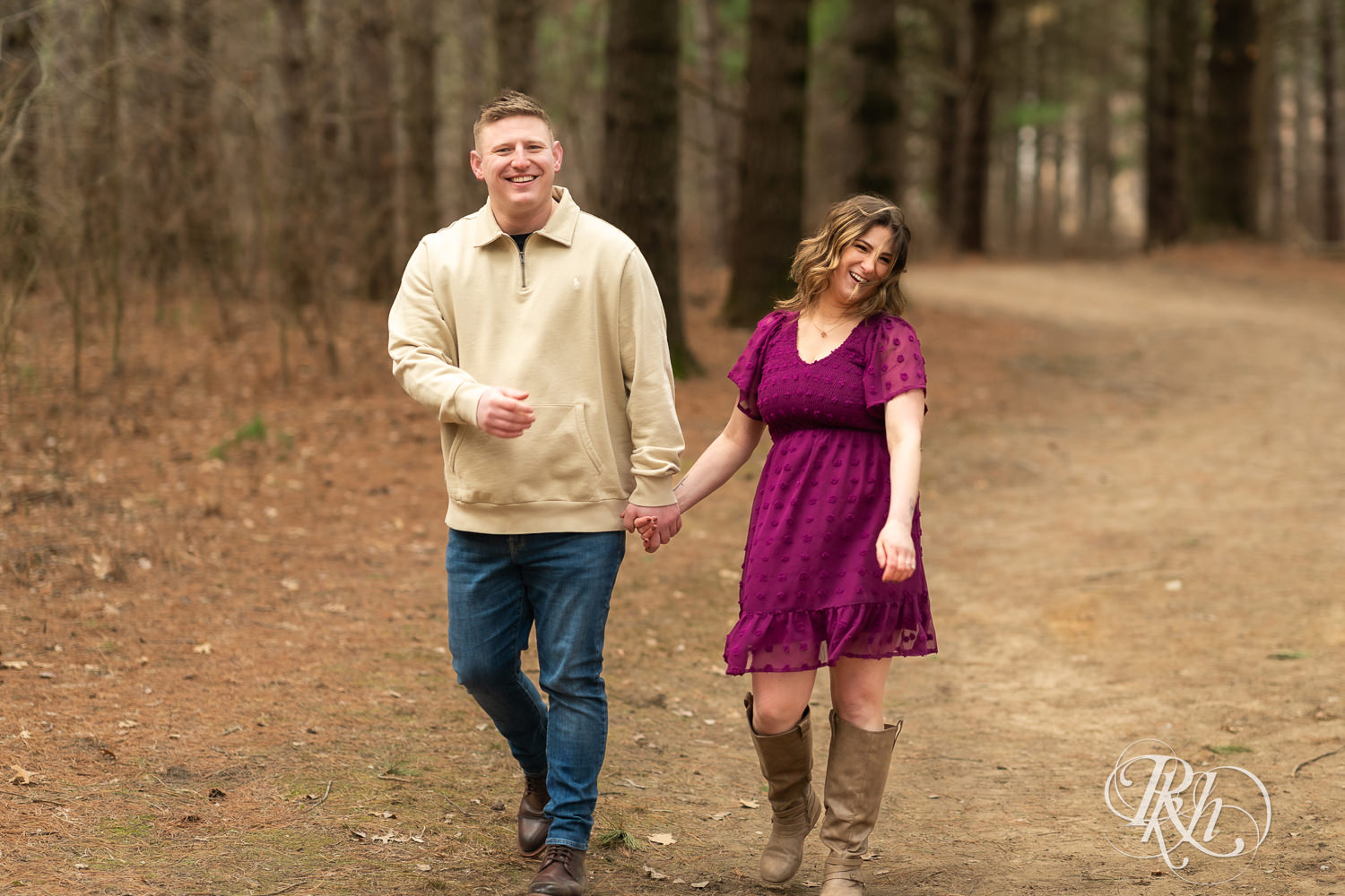 Man in jeans and woman in magenta dress laugh while walking through the woods in Lebanon Hills in Eagan, Minnesota.