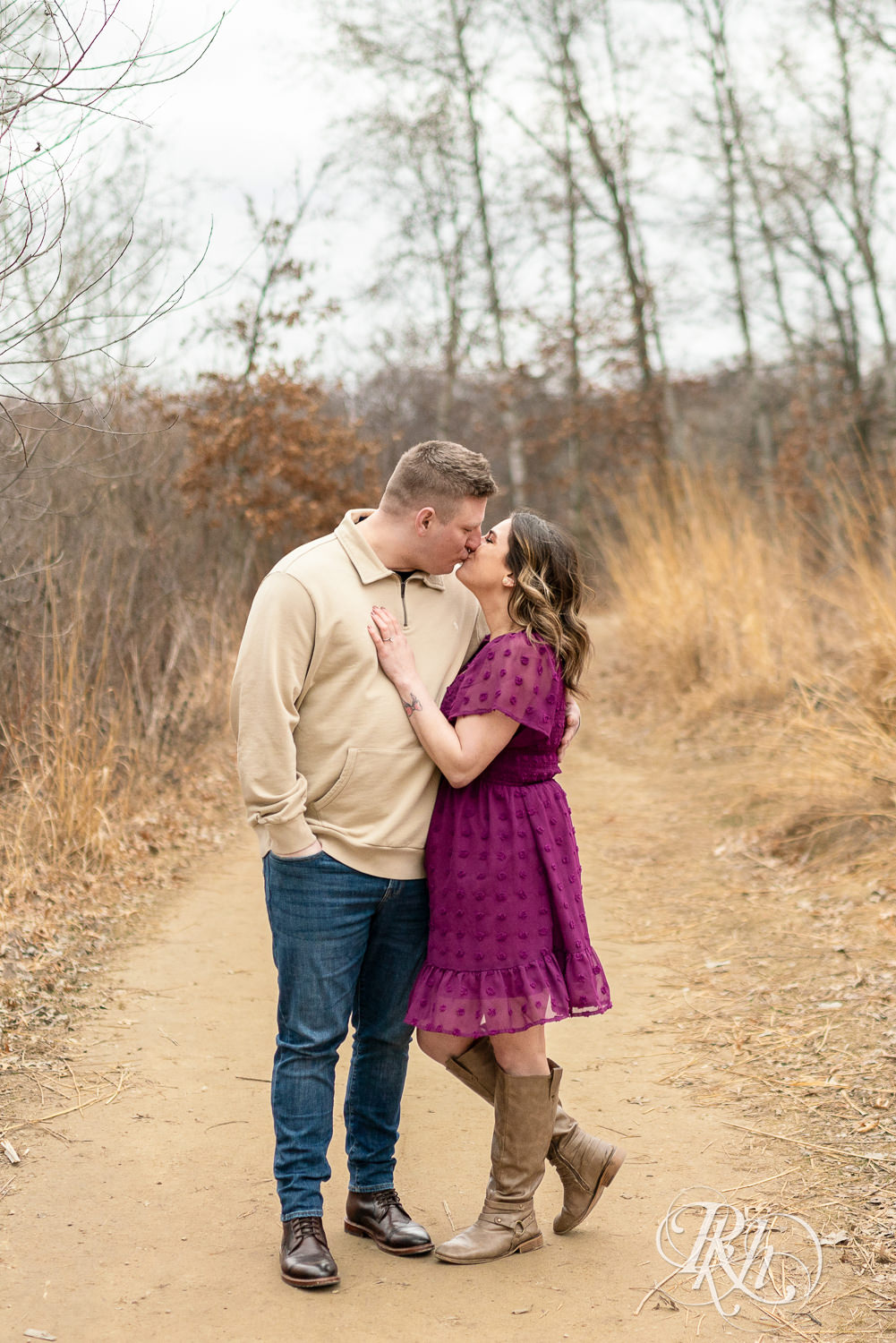 Man in jeans and woman in magenta dress kiss during March engagement photography in Eagan, Minnesota.