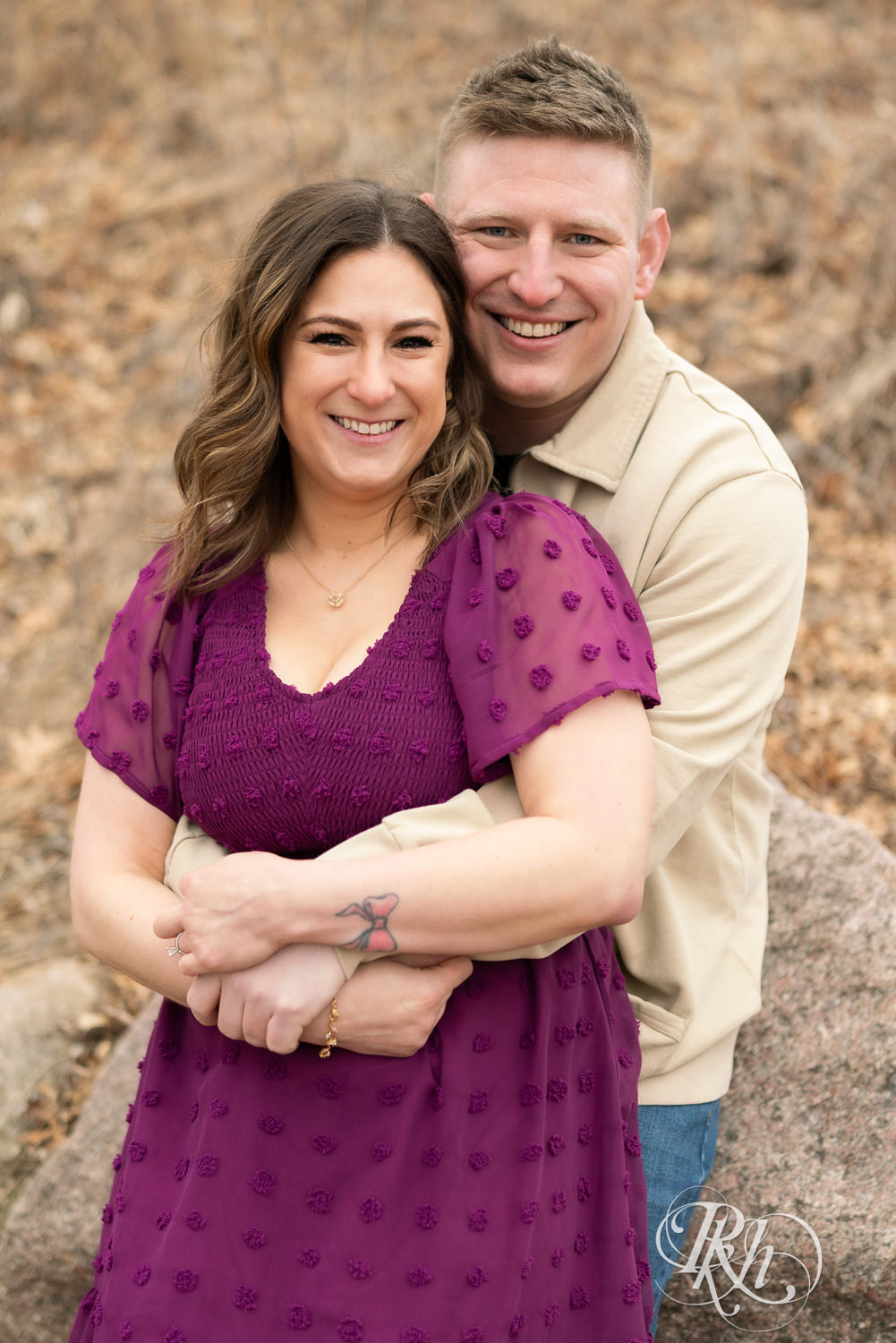 Man in jeans and woman in magenta dress smile during March engagement photography in Eagan, Minnesota.