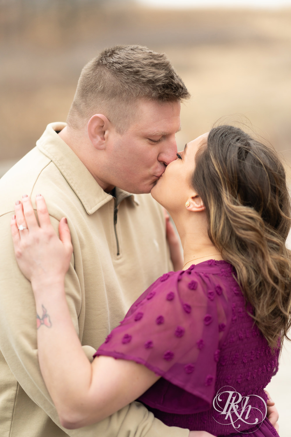 Man in jeans and woman in magenta dress kiss during March engagement photography in Eagan, Minnesota.