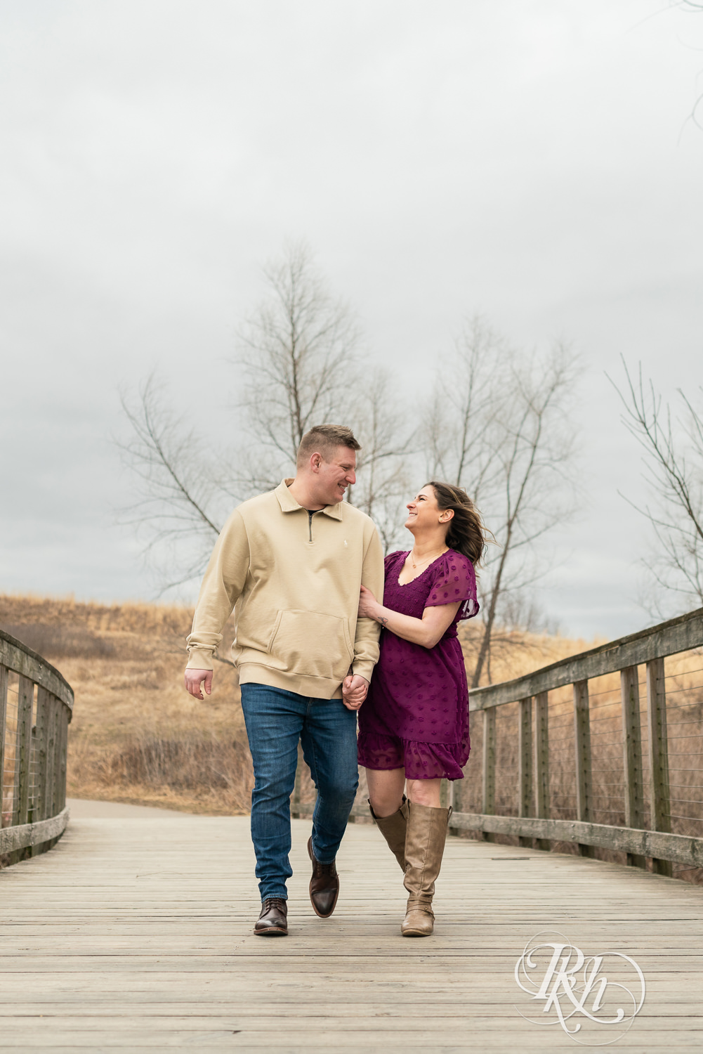 Man in jeans and woman in magenta dress laugh while walking on a bridge in Lebanon Hills in Eagan, Minnesota.